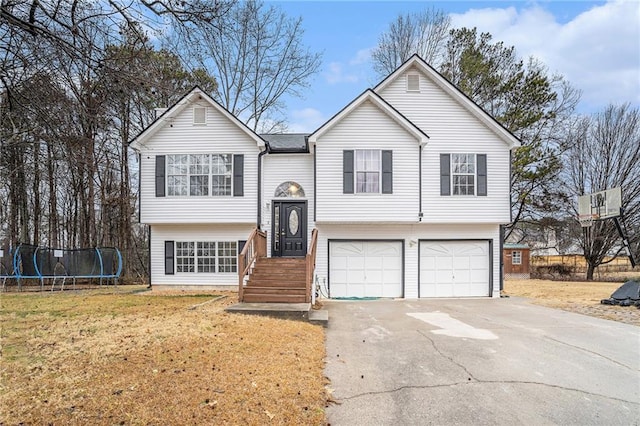 bi-level home featuring a garage, a front lawn, and a trampoline