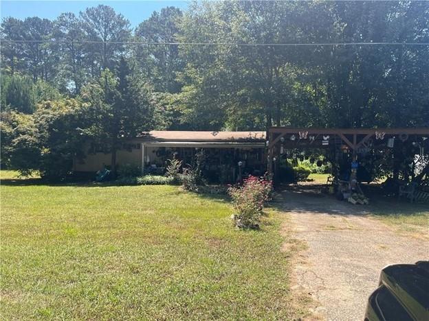 view of green lawn with a carport and driveway