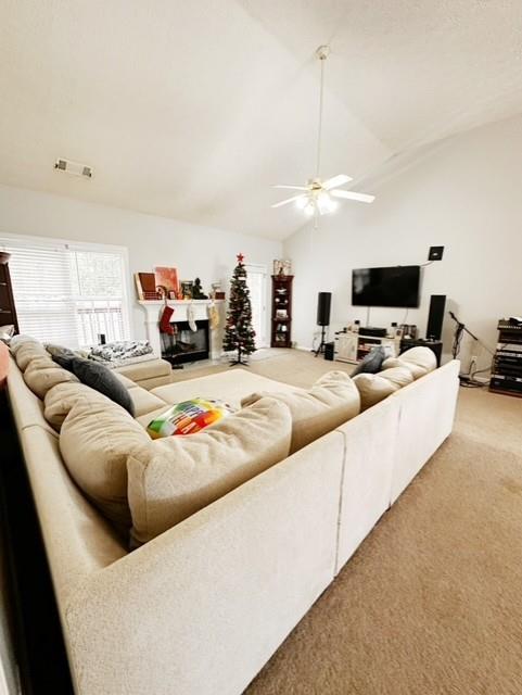 living room featuring ceiling fan, carpet floors, and vaulted ceiling