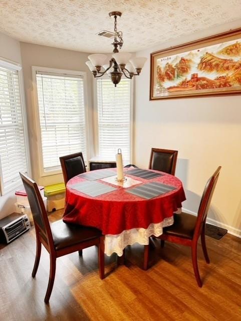 dining space with hardwood / wood-style floors, an inviting chandelier, and a textured ceiling