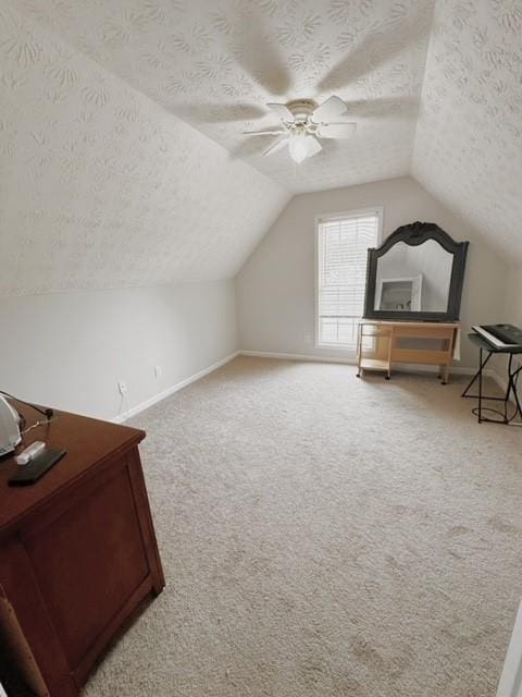 additional living space with carpet flooring, ceiling fan, vaulted ceiling, and a textured ceiling