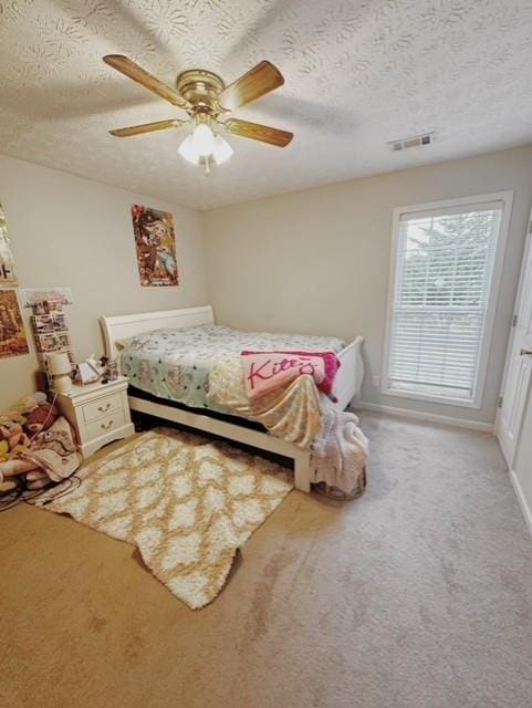 carpeted bedroom featuring ceiling fan and a textured ceiling