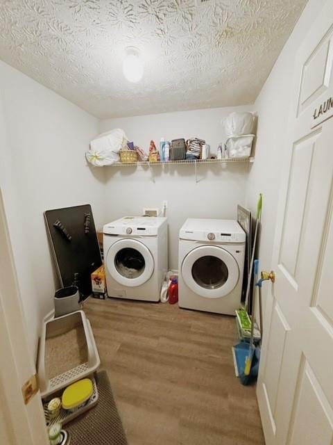 laundry room featuring wood-type flooring, a textured ceiling, and washer and clothes dryer