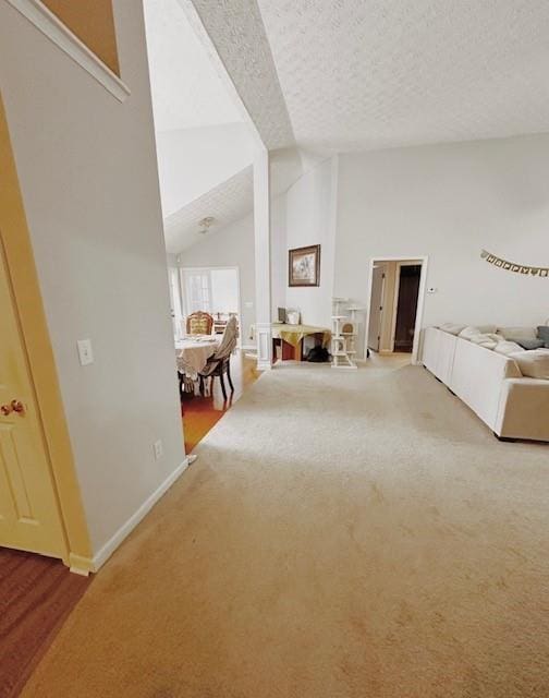 unfurnished living room featuring lofted ceiling, carpet floors, and a textured ceiling