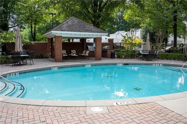 community pool with fence, a gazebo, a patio, and outdoor dining area