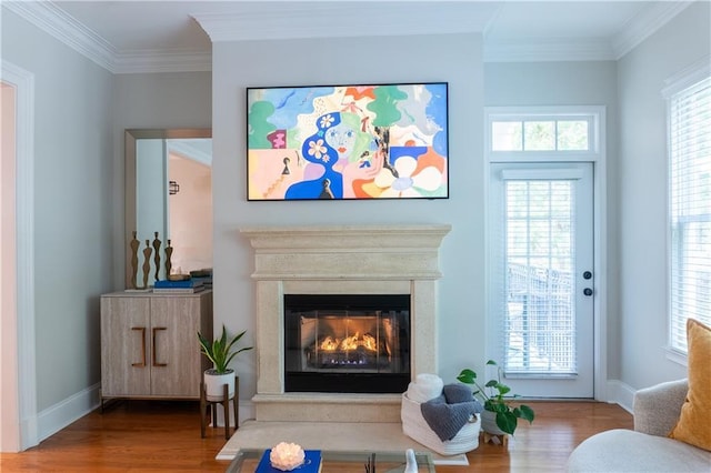 living area with ornamental molding, wood finished floors, a high end fireplace, and baseboards