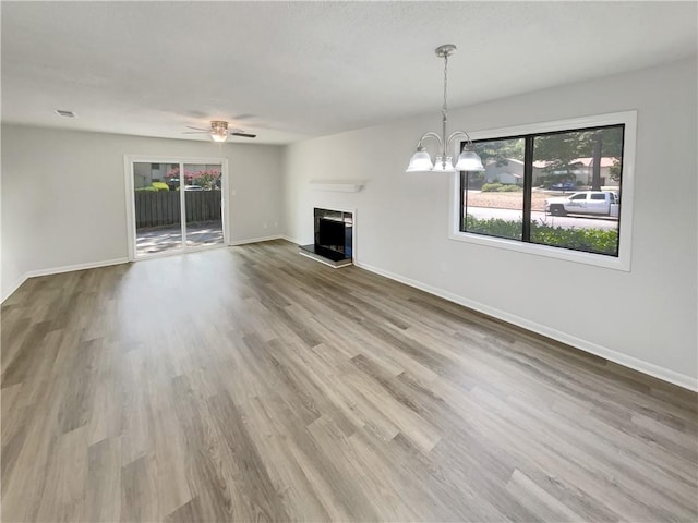 1152 Country Ct, Lawrenceville, GA 30044 - unfurnished living room featuring a fireplace with raised hearth, wood finished floors, a chandelier, and a ceiling fan