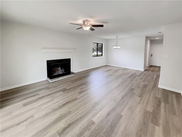 1152 Country Ct, Lawrenceville, GA 30044 - unfurnished living room with a ceiling fan, a fireplace with raised hearth, wood finished floors, and a chandelier
