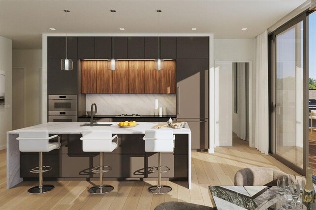 kitchen with light wood-style flooring, a sink, backsplash, modern cabinets, and a kitchen bar