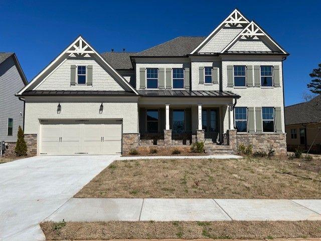 craftsman house featuring a porch, a standing seam roof, concrete driveway, and stone siding