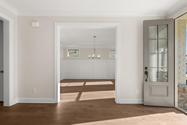 interior space featuring baseboards, ornamental molding, wood finished floors, and a chandelier