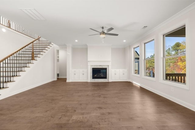 unfurnished living room with crown molding, stairs, wood finished floors, baseboards, and a ceiling fan