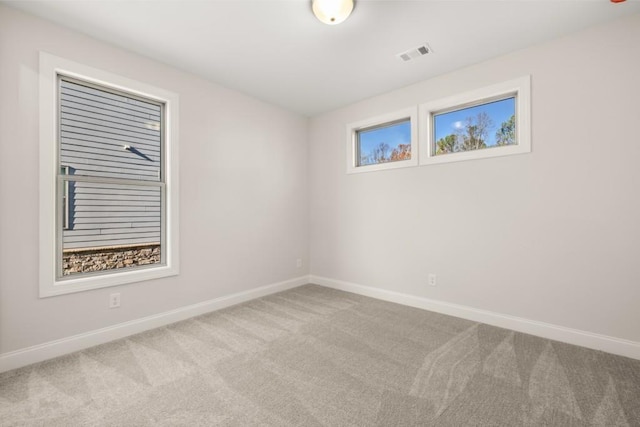 carpeted spare room with visible vents and baseboards