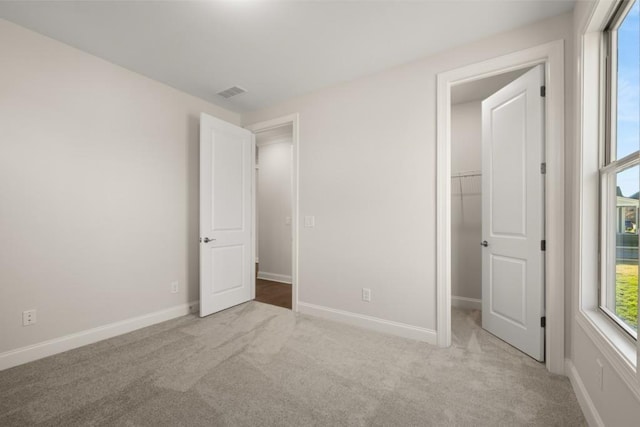 unfurnished bedroom with visible vents, carpet, baseboards, and a spacious closet
