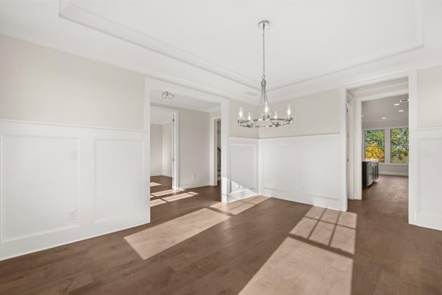 unfurnished dining area with a tray ceiling, a decorative wall, and a chandelier