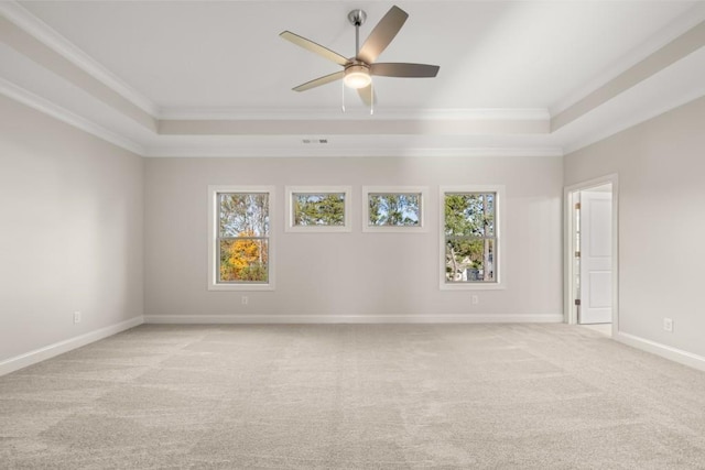 unfurnished room featuring crown molding, a tray ceiling, light colored carpet, and a healthy amount of sunlight