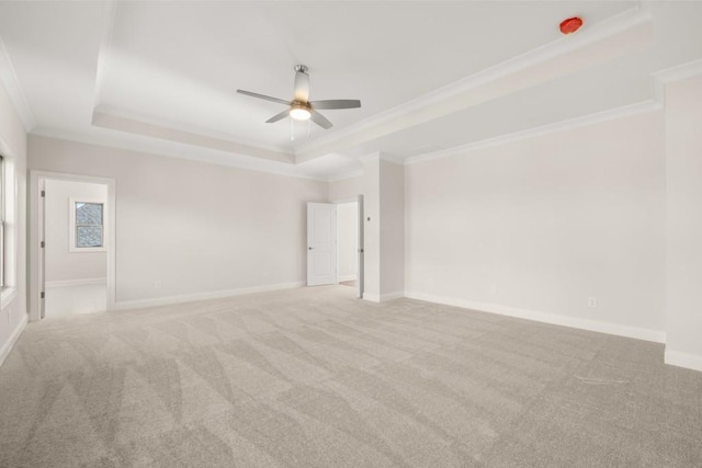 carpeted spare room featuring crown molding, a raised ceiling, ceiling fan, and baseboards