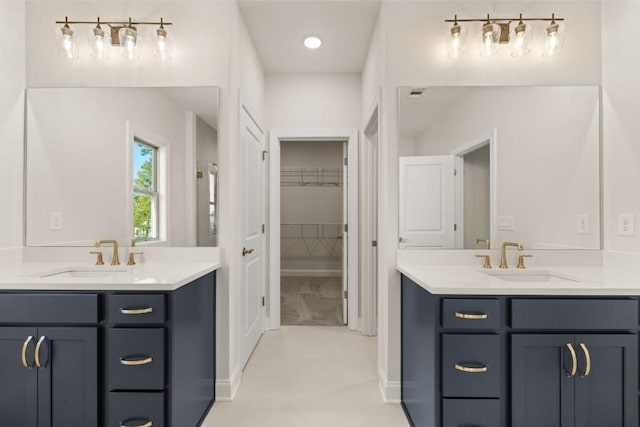 bathroom with a sink, two vanities, and a spacious closet