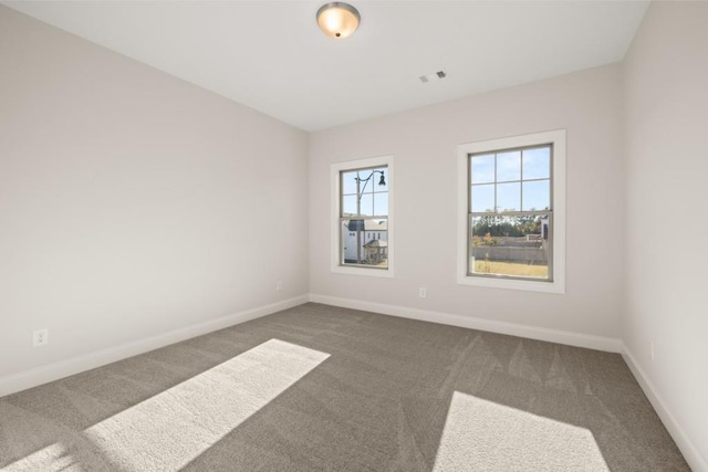 carpeted spare room featuring baseboards and visible vents