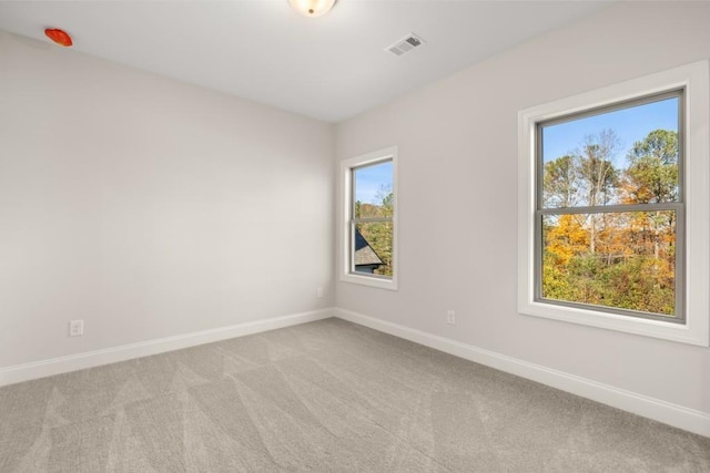 empty room featuring baseboards, visible vents, and light carpet