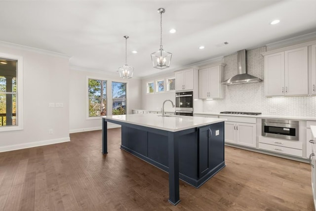 kitchen featuring light countertops, ornamental molding, a healthy amount of sunlight, and wall chimney exhaust hood