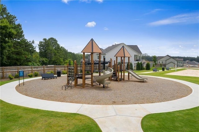 communal playground featuring a lawn and fence