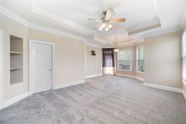 interior space featuring built in shelves, baseboards, crown molding, and a tray ceiling