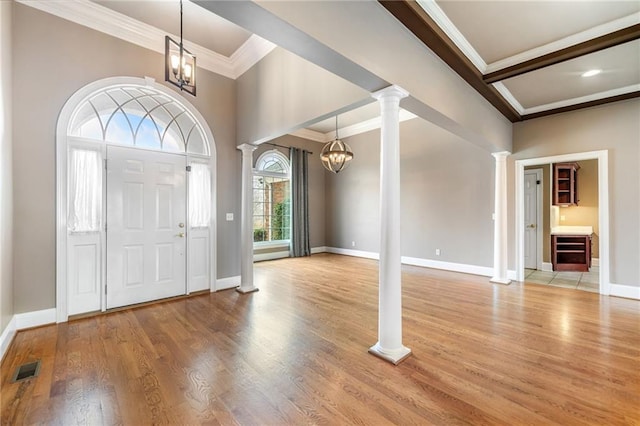 entryway with light wood-type flooring, decorative columns, visible vents, and an inviting chandelier