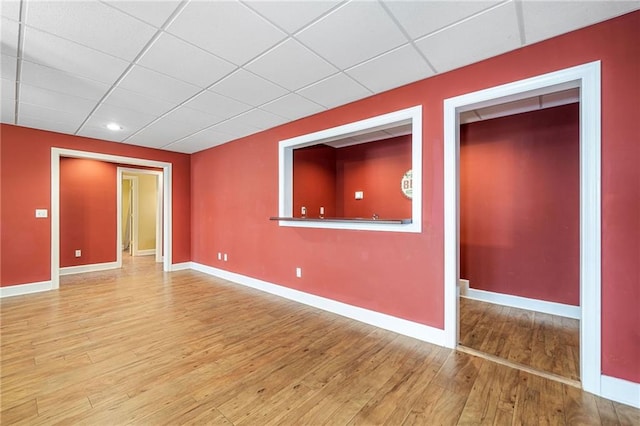 unfurnished room with wood finished floors, baseboards, and a drop ceiling