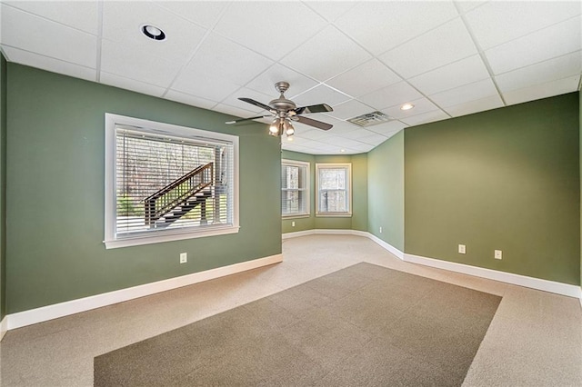 carpeted spare room with a ceiling fan, visible vents, baseboards, and a paneled ceiling