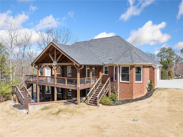 back of house with brick siding, a shingled roof, stairs, and a deck