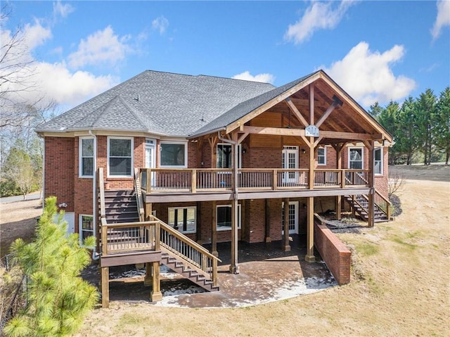 back of property with brick siding, stairway, a shingled roof, and a deck