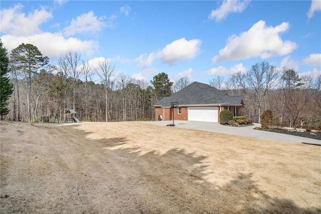 view of property exterior featuring driveway, a playground, a yard, a garage, and brick siding