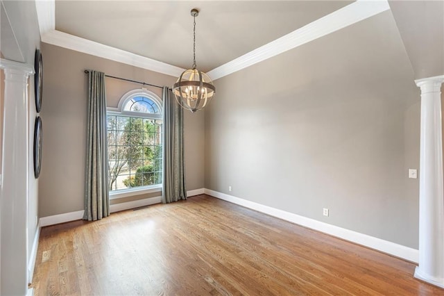 unfurnished dining area featuring ornamental molding, wood finished floors, baseboards, and decorative columns