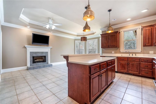 kitchen with a tray ceiling, ornamental molding, light countertops, and a sink