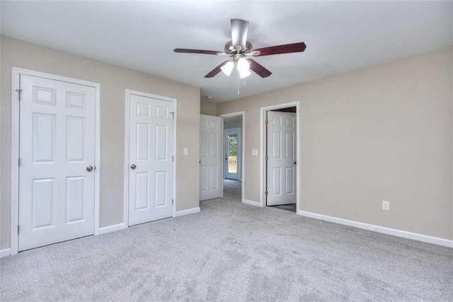 unfurnished bedroom with ceiling fan, carpet floors, and two closets