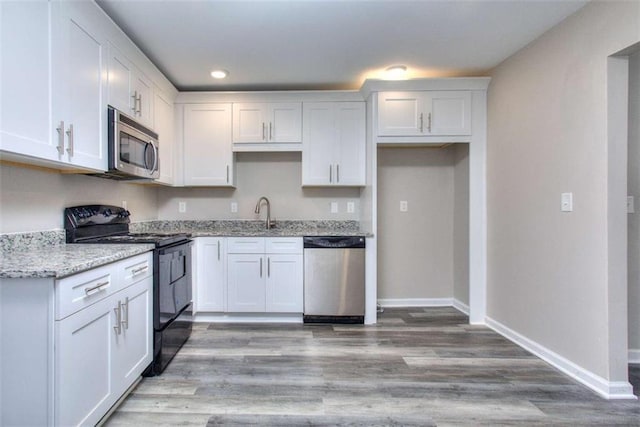 kitchen with white cabinetry, stainless steel appliances, light stone countertops, light hardwood / wood-style flooring, and sink