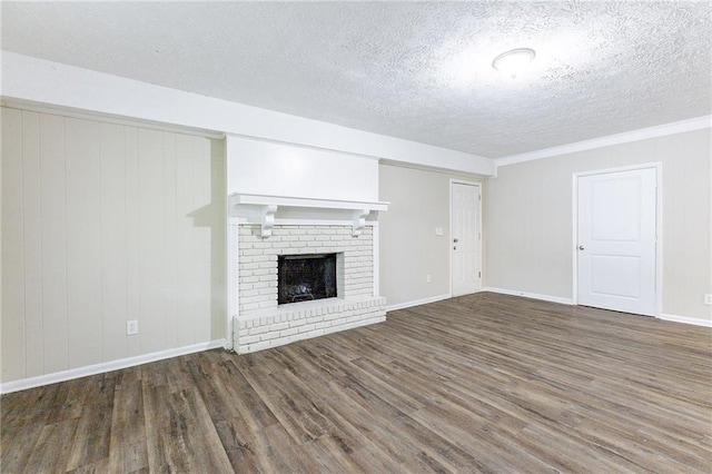 unfurnished living room with a textured ceiling, a fireplace, dark hardwood / wood-style floors, and crown molding