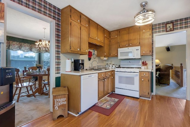 kitchen with light countertops, white appliances, light wood-type flooring, and a sink