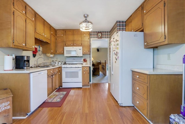kitchen featuring white appliances, light countertops, a sink, and light wood-style flooring
