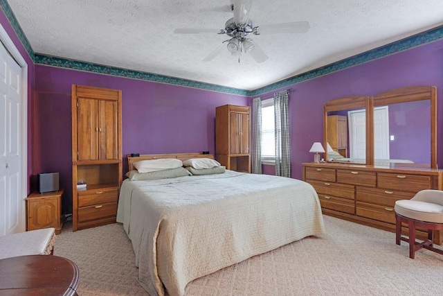 carpeted bedroom with a closet, ceiling fan, and a textured ceiling