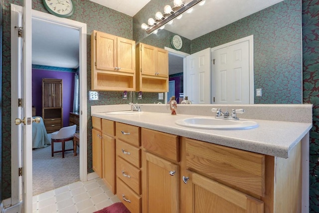 bathroom with double vanity, a sink, and wallpapered walls
