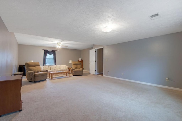 living area featuring baseboards, visible vents, a ceiling fan, a textured ceiling, and carpet floors