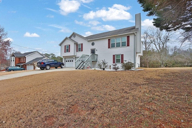 raised ranch featuring a garage, driveway, a chimney, and a front lawn