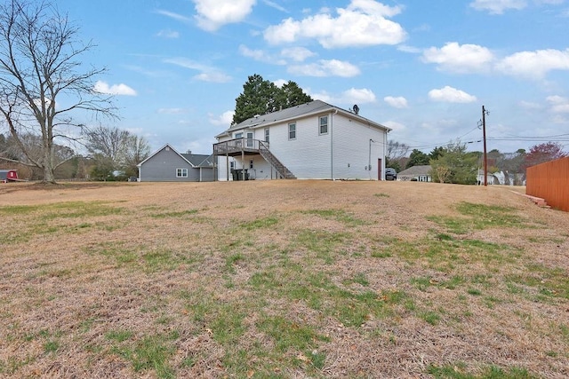 rear view of property featuring a yard, stairway, and a wooden deck
