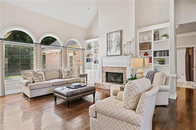 997 Thousand Oaks Bnd NW, Kennesaw, GA 30152 - living room with high vaulted ceiling, built in shelves, wood finished floors, a brick fireplace, and baseboards