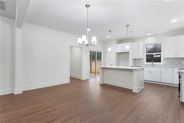 kitchen with white cabinetry, a kitchen island, decorative backsplash, and decorative light fixtures