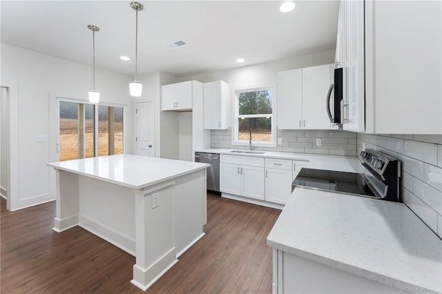 kitchen featuring appliances with stainless steel finishes, sink, white cabinets, decorative backsplash, and a center island