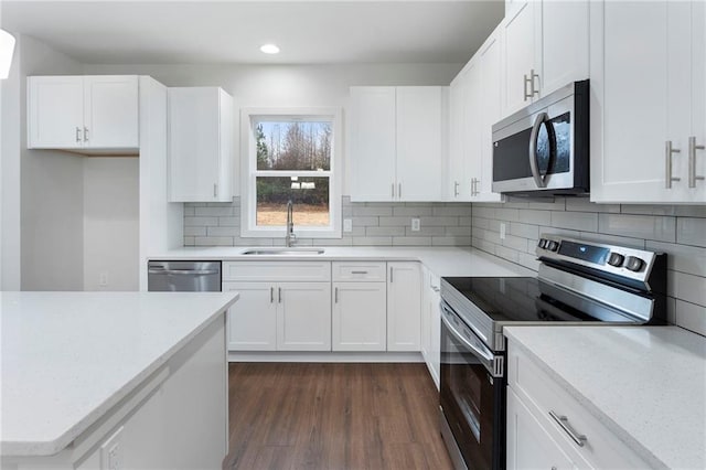 kitchen with sink, white cabinetry, stainless steel appliances, dark hardwood / wood-style floors, and decorative backsplash