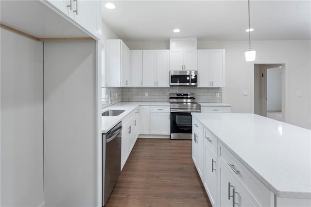 kitchen with sink, hanging light fixtures, white cabinets, stainless steel appliances, and backsplash